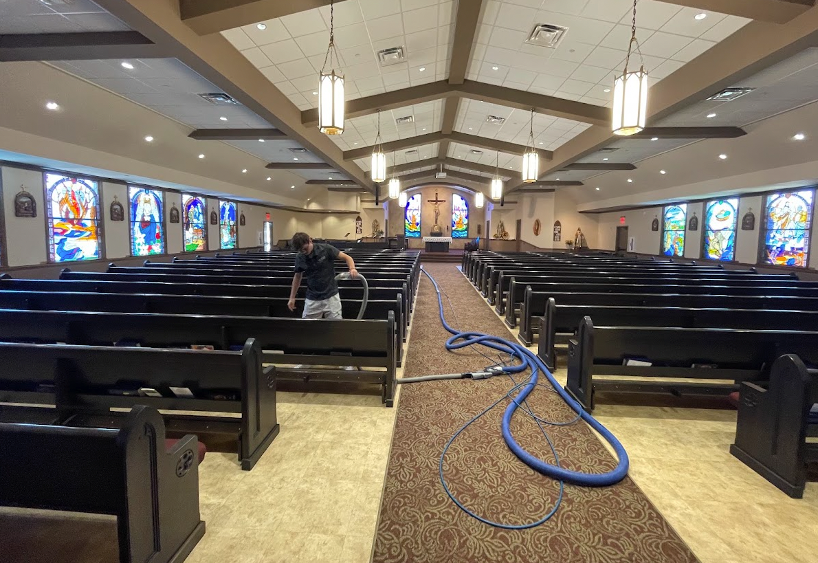 RJH and Sons technician deep cleaning carpet between the pews of a Texas Hill Country church