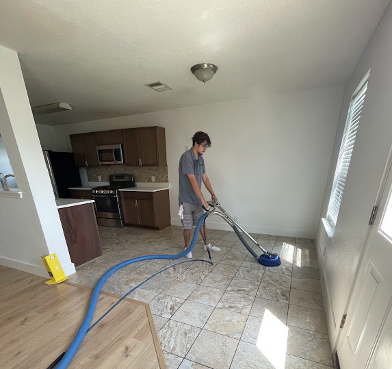 Technician cleaning tile and grout with a rotary spinner tool in a Dripping Springs home